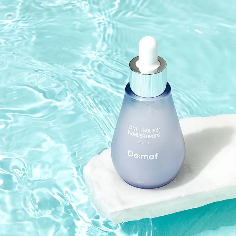 bareskin.lt Demaf Panthenol 30% Wonder Drops ampoule serum in a blue glass bottle resting on white stone in water