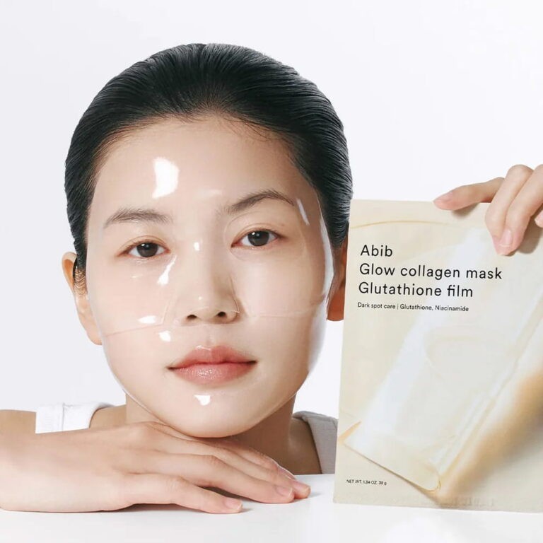 Woman with clear skin wearing an Abib Glow Collagen Mask Glutathione Film, holding the product packaging
