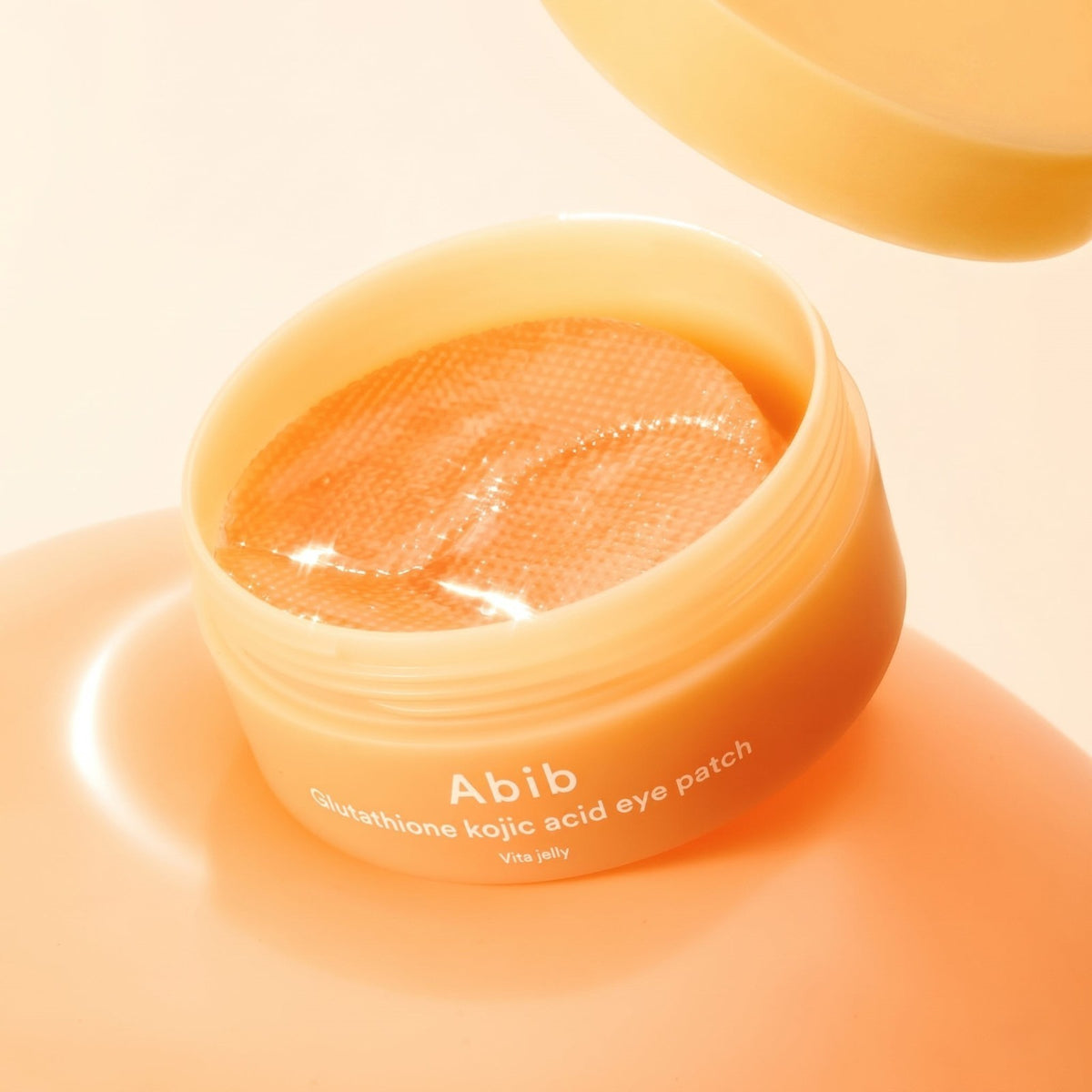 bareskin.lt Abib Vita Jelly Glutathione Kojic Acid hydrogel eye patches in an open orange jar on a matching surface.