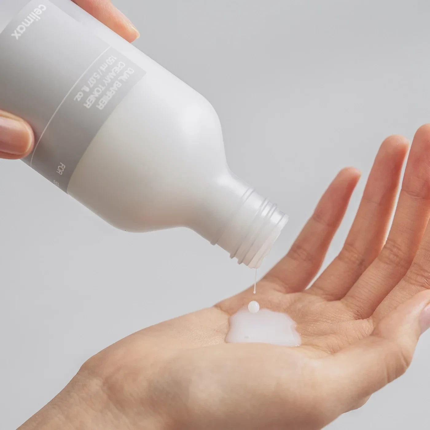 Celimax Dual Barrier Creamy Toner from bareskin.lt being poured into a hand showing the milky white texture