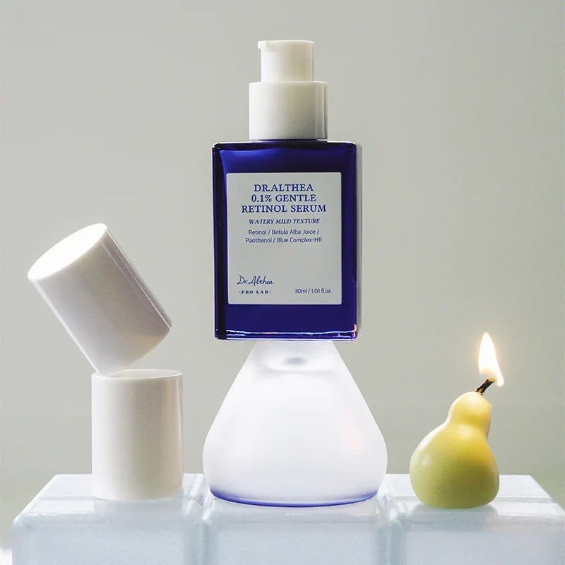 Dr.Althea 0.1 Gentle Retinol Serum in a blue glass bottle on a glass stand with a pear candle from bareskin.lt