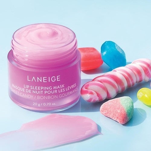 LANEIGE Lip Sleeping Mask Sweet Candy in a pink jar by bareskin.lt, surrounded by colorful candy on blue background.