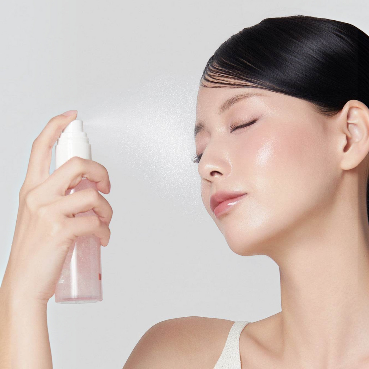 Model applying bareskin.lt Medicube PDRN Pink Collagen Glow Jelly Mist Serum to her face for a radiant finish