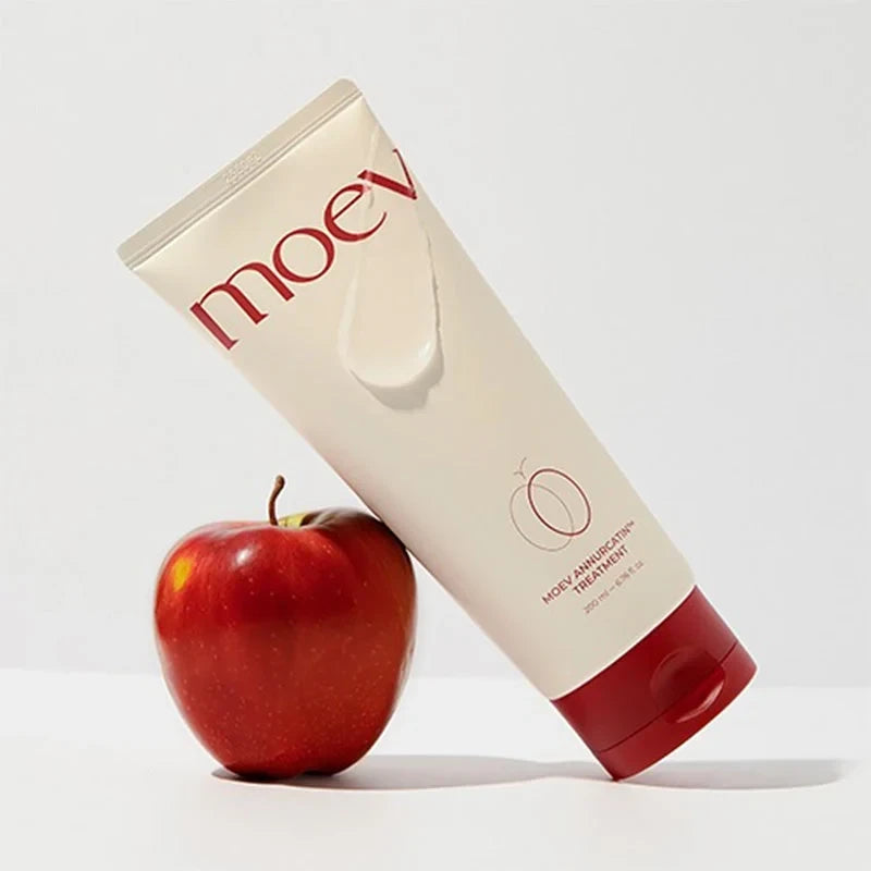 bareskin.lt MOEV Annurcatin hair treatment conditioner in a beige tube with a red cap next to a fresh red apple