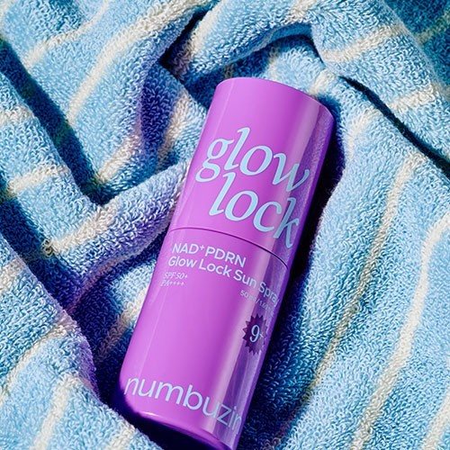 bareskin.lt Numbuzin No.9 NAD+ PDRN Glow Lock Sun Spray in a purple bottle resting on a blue striped towel