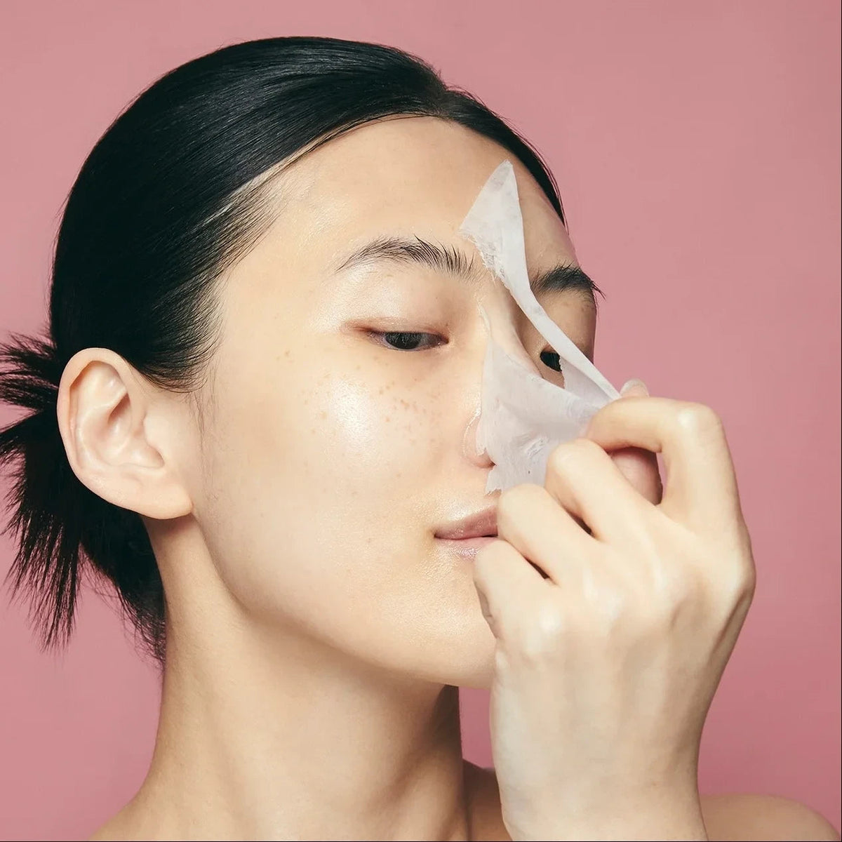 Woman applying a Purito Multi Pdrn Collagen Real Glow Mask on her face, sold by bareskin.lt