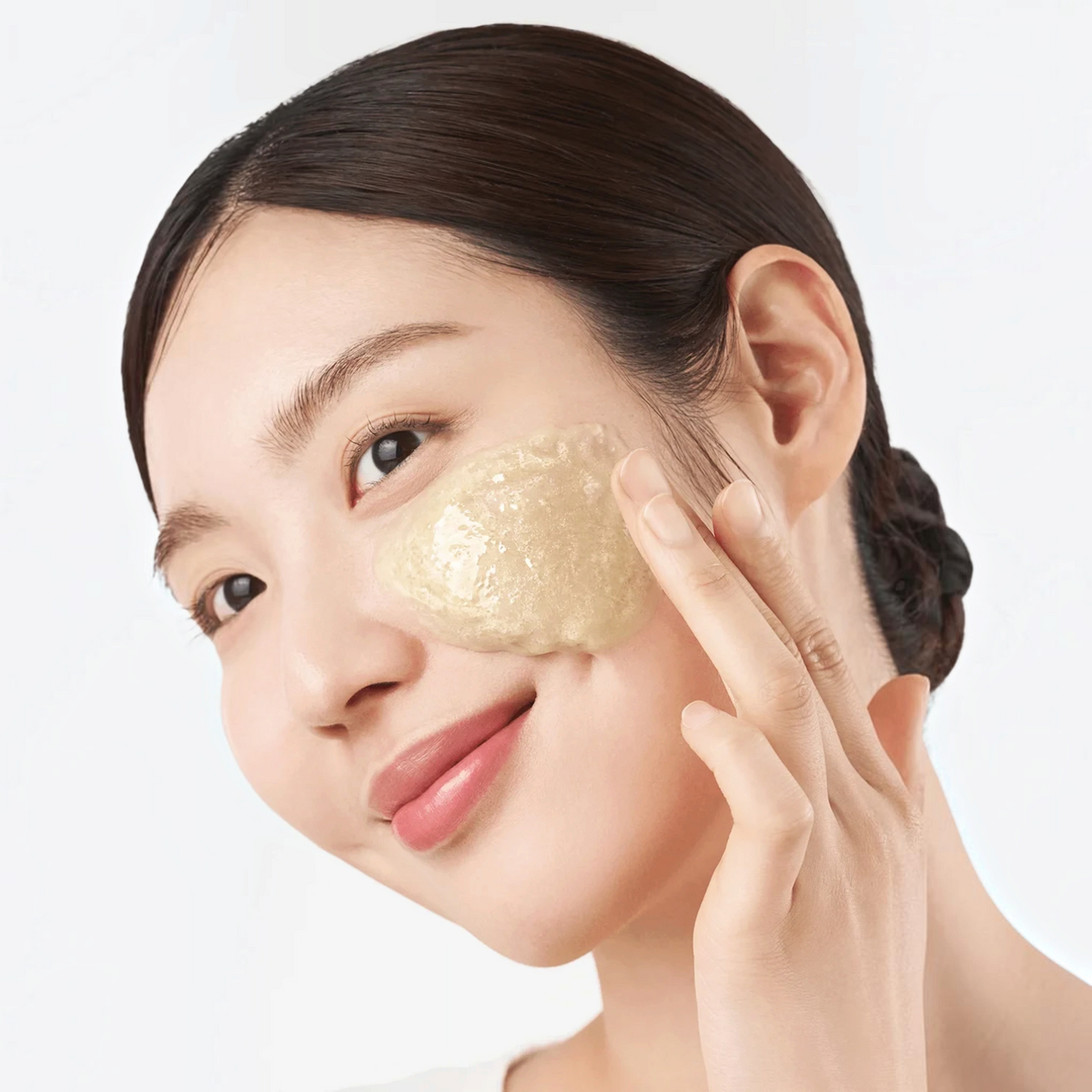 Woman applying Purito SEOUL Oat In Gentle Exfoliating Face Cleanser to her cheek for a bareskin.lt skincare routine.