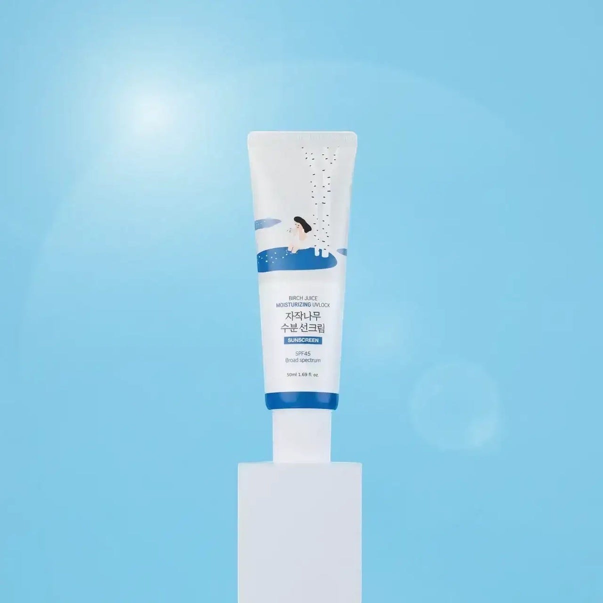 bareskin.lt Round Lab Birch Juice Moisturizing Sun Cream SPF50+ in a white tube on a pedestal against a blue background