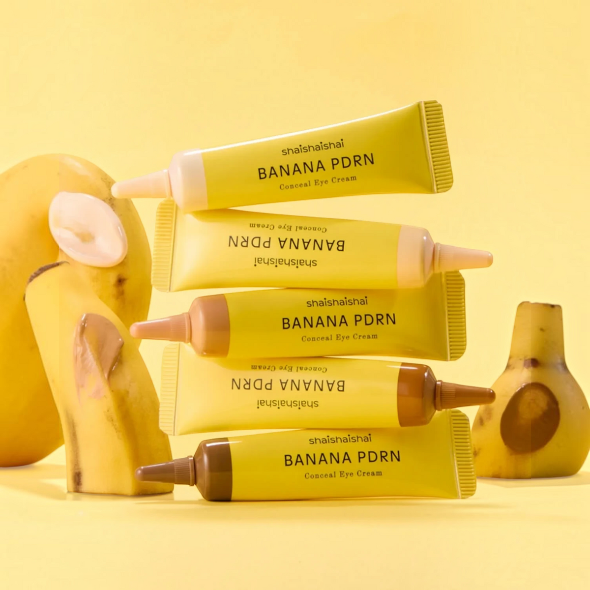 bareskin.lt shaishaishai Banana PDRN Conceal Eye Cream tubes in various shades stacked with fresh banana slices