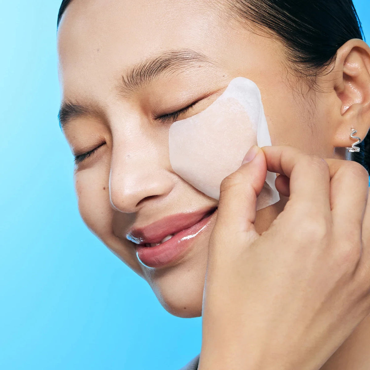 Model applying a bareskin.lt Torriden DIVE-IN hyaluronic acid essence pad to her cheek for deep skin hydration