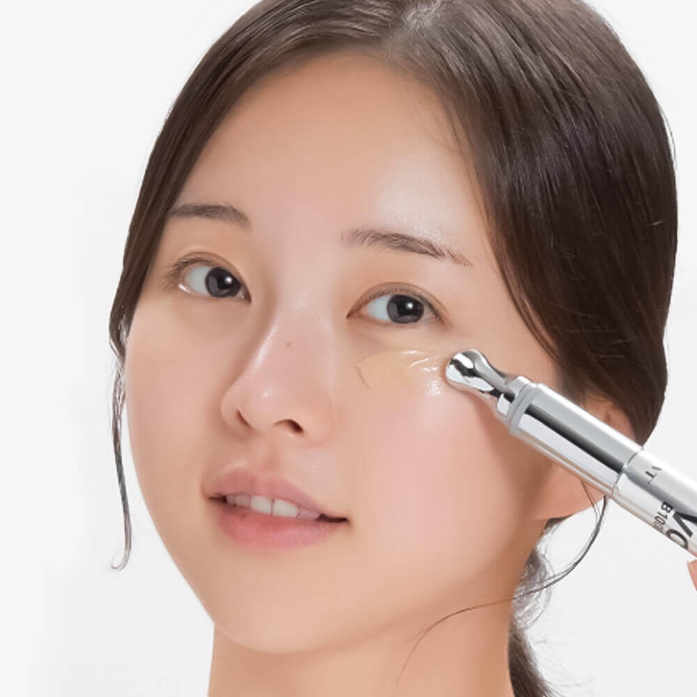 Woman applying VT Cosmetics Reedle Shot Vita-Light eye cream with a metal applicator for brightening and hydration.