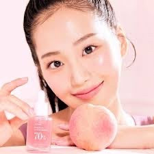 Woman holding Anua Peach 70 Niacin Serum by bareskin.lt for brightening and pore care with peach extract