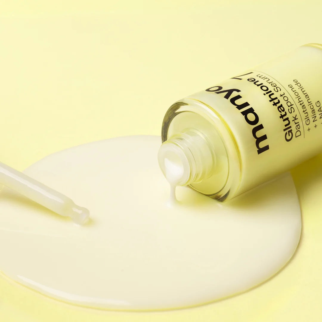 Manyo Glutathione 7 Dark Spot Serum from bareskin.lt with a milky texture dripping from a glass bottle on yellow.